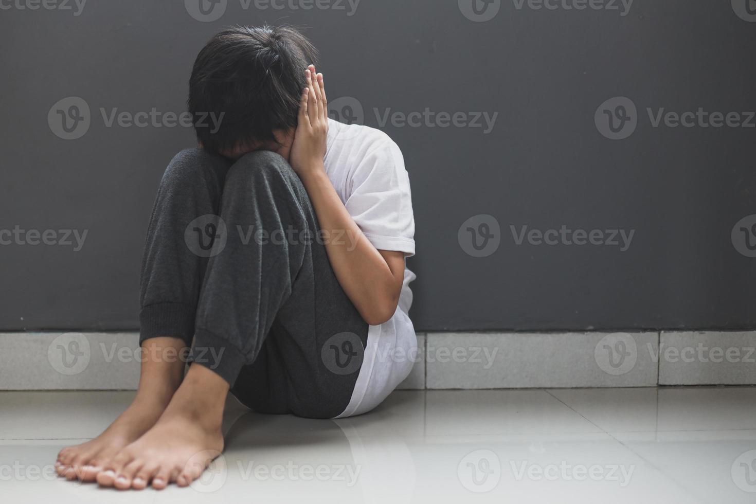 Scared boy sitting and covering his ear with hand photo