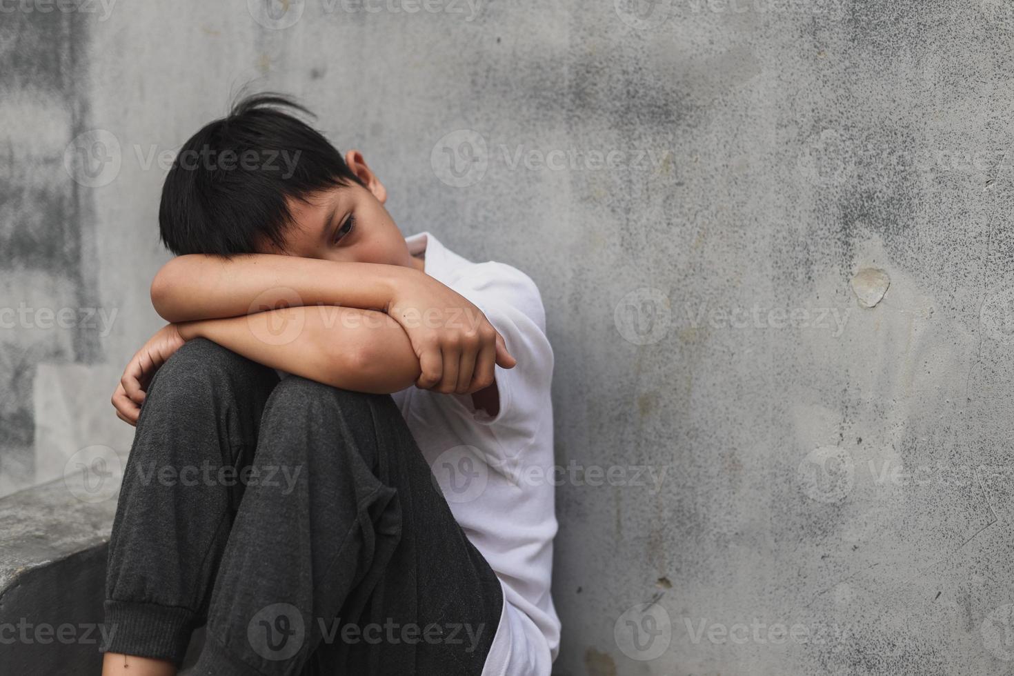 Boy sitting alone after suffering an act of bullying or abusing photo