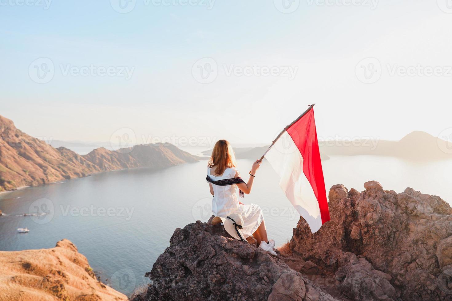 una mujer de pie en la cima de las colinas y sosteniendo la bandera de indonesia en la isla de padar labuan bajo foto