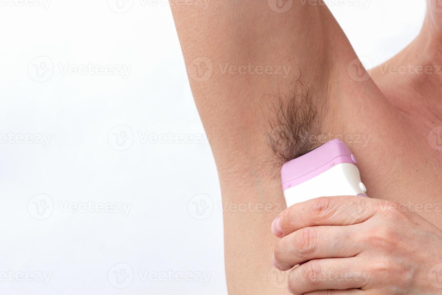 Hand removing hair from armpit by epilator photo