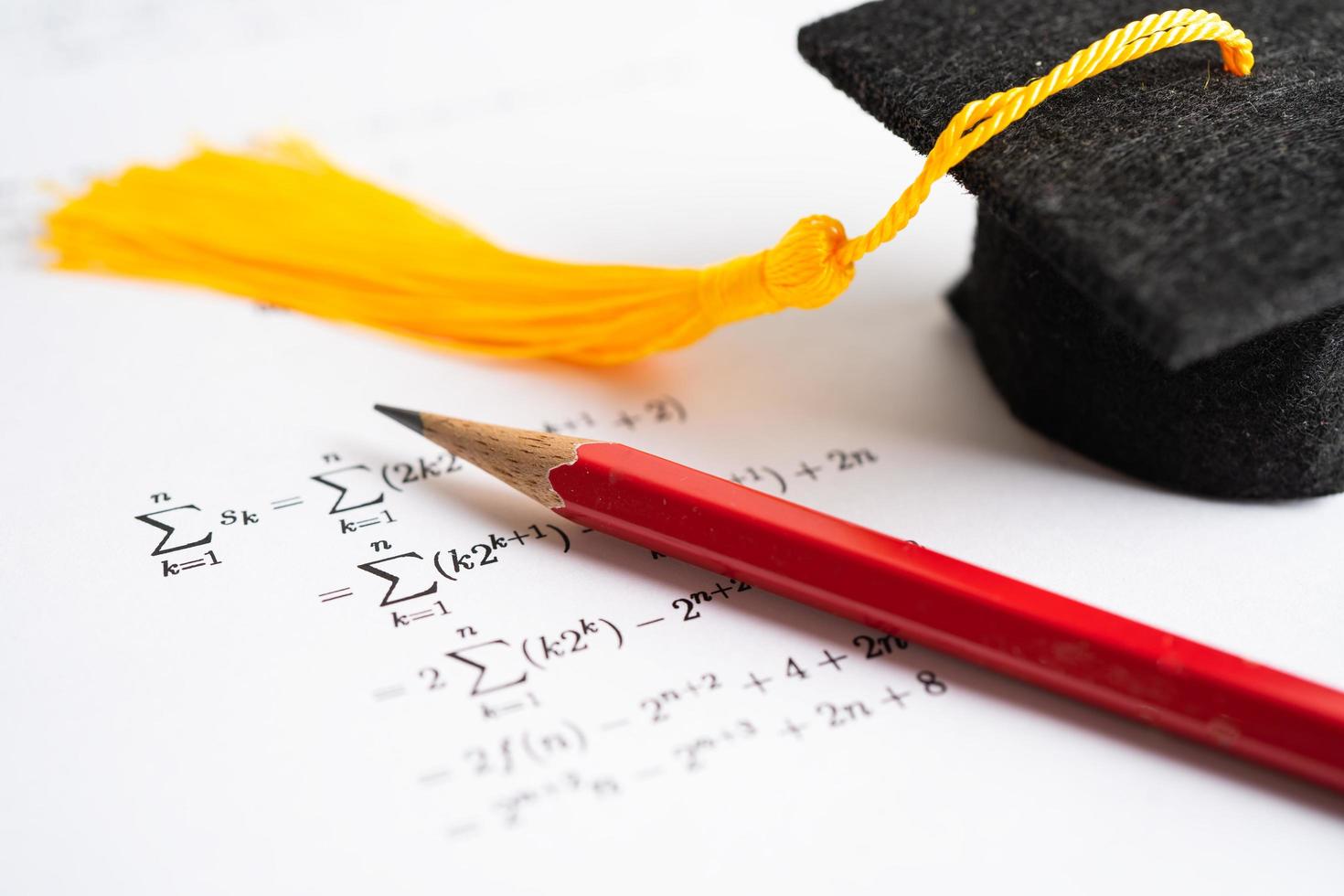 sombrero de brecha de graduación y lápiz en papel de prueba de ejercicio de fórmula matemática en la escuela de educación. foto