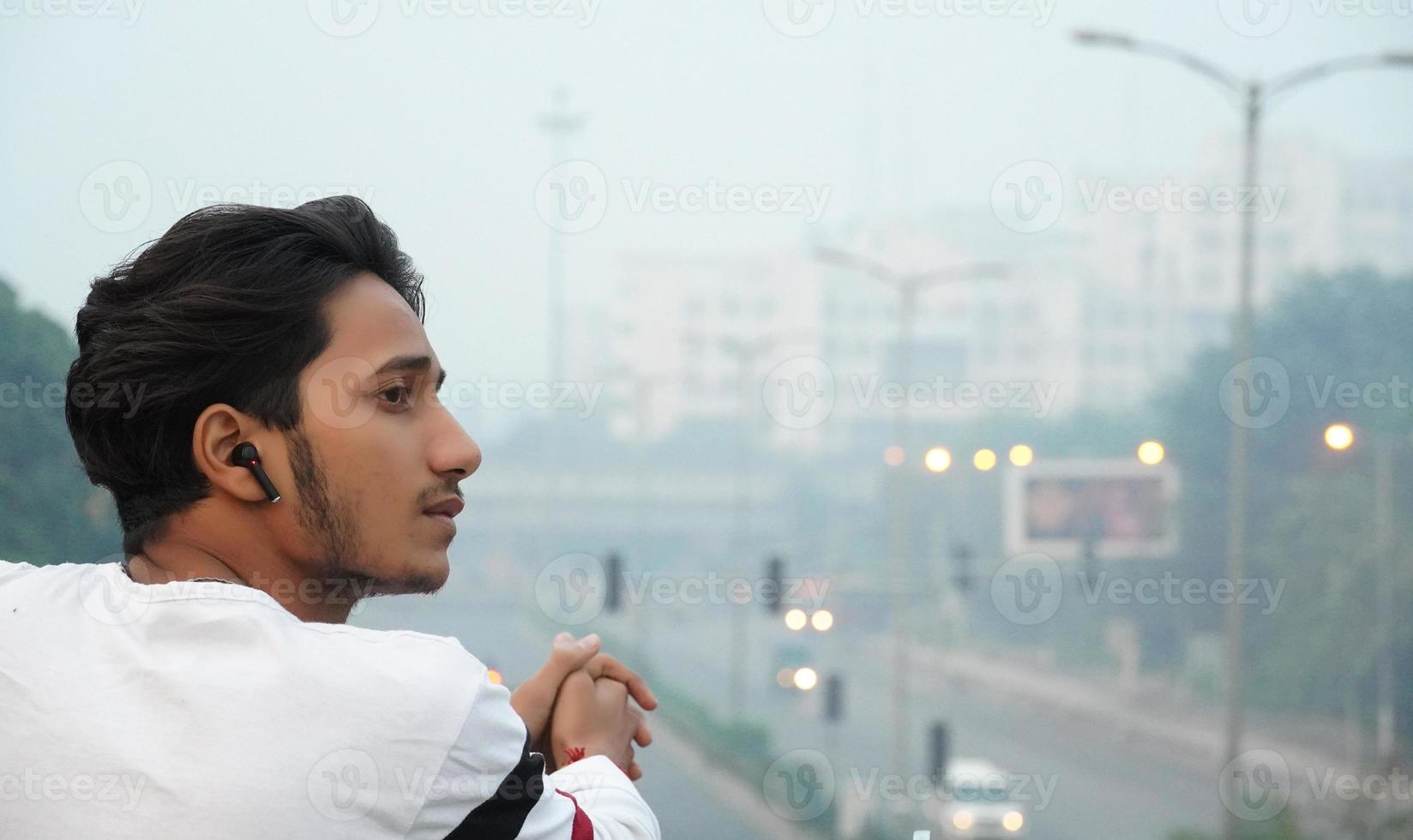 indian man standing on flyover bridge and listening music photo