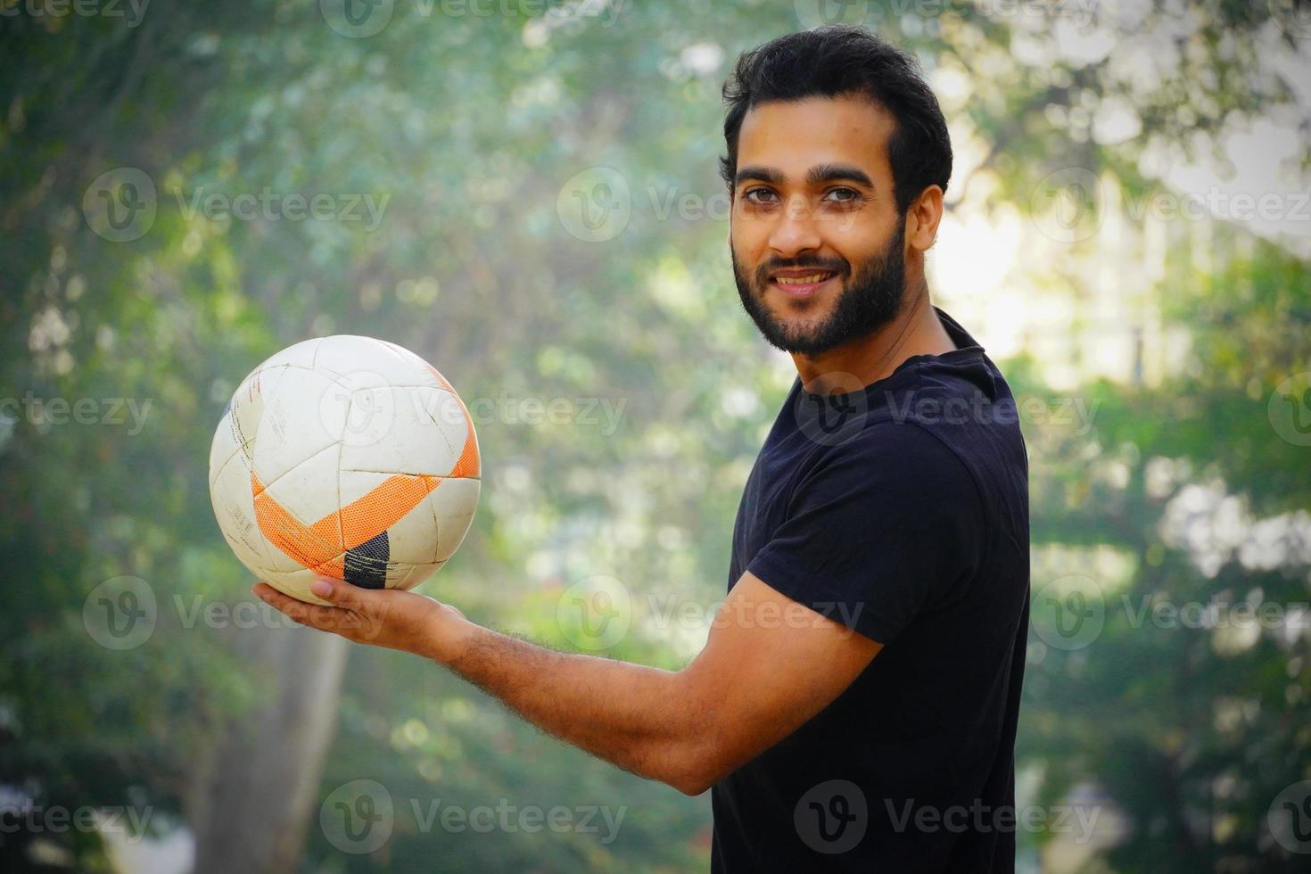 jugador de fútbol joven que tiene la imagen de la pelota en la mano foto