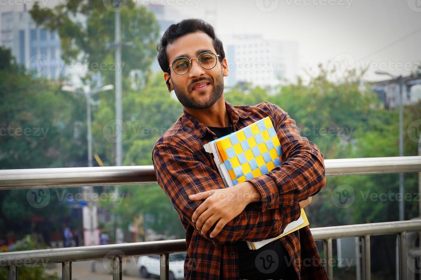 estudiante sosteniendo imágenes de libros un joven estudiante universitario con libros cerca del campus universitario foto