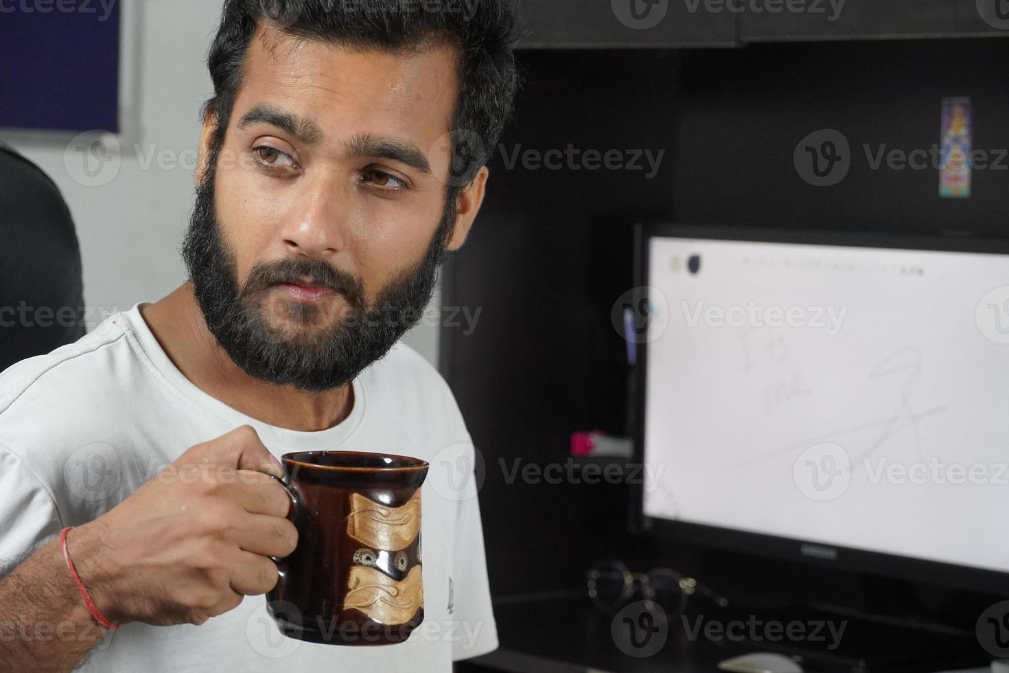 un hombre en la mesa de la computadora y tomando una taza de café foto