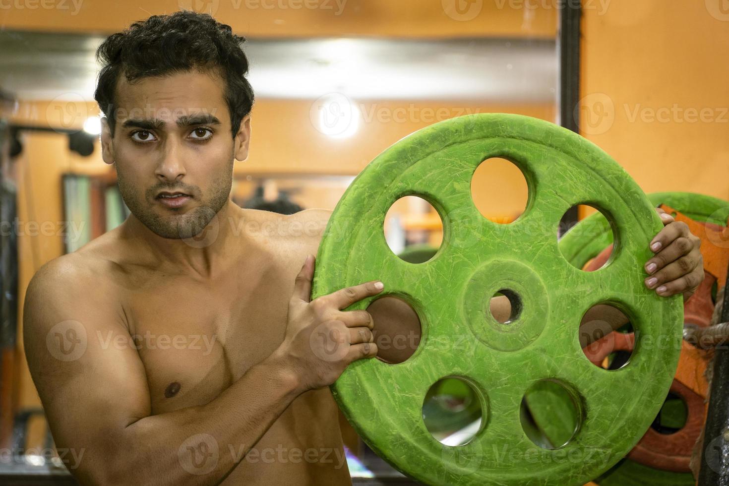Young man in gym with gym plate going to lift weight photo