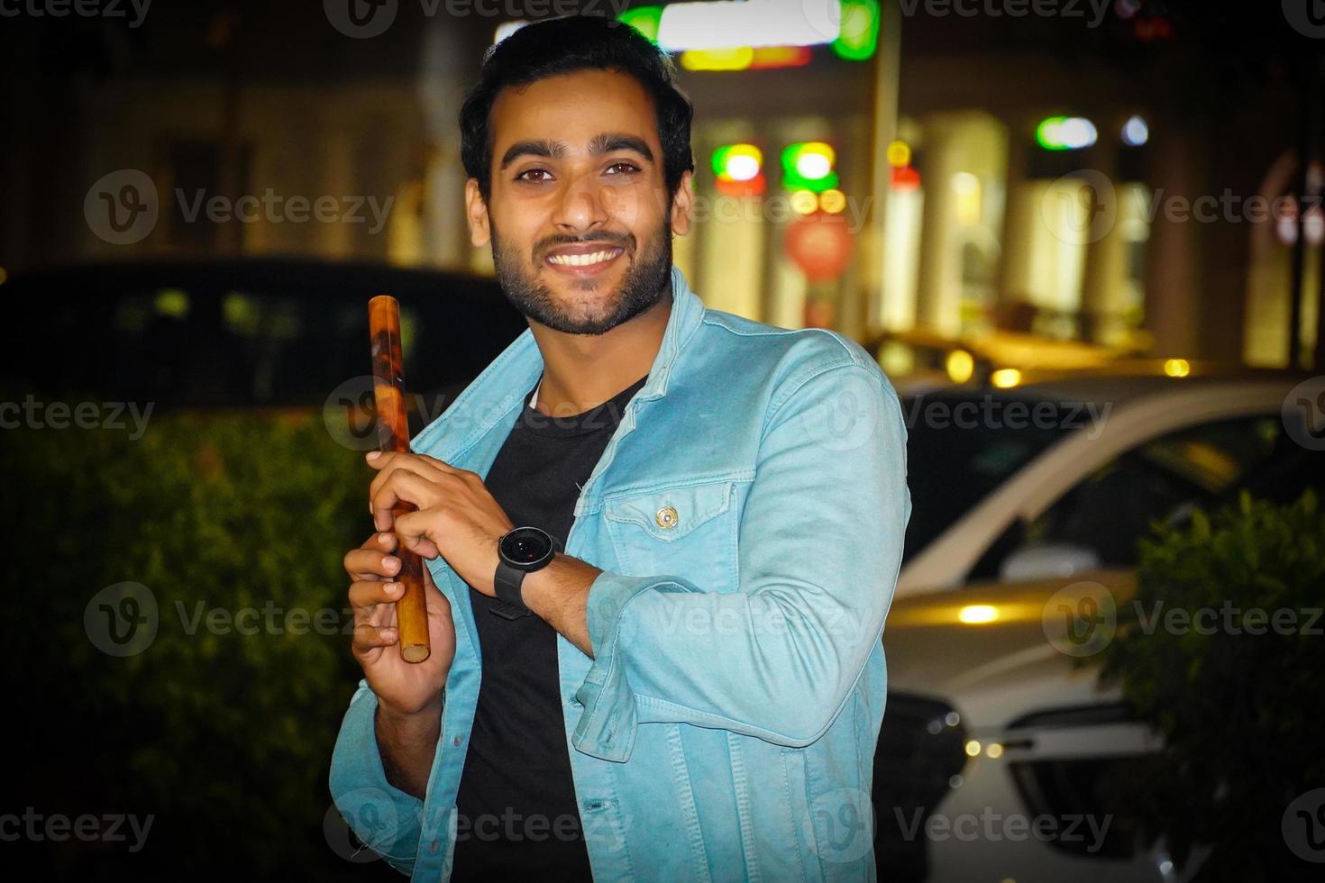 A young Indian man having bansuri Indian flute and giving smile photo