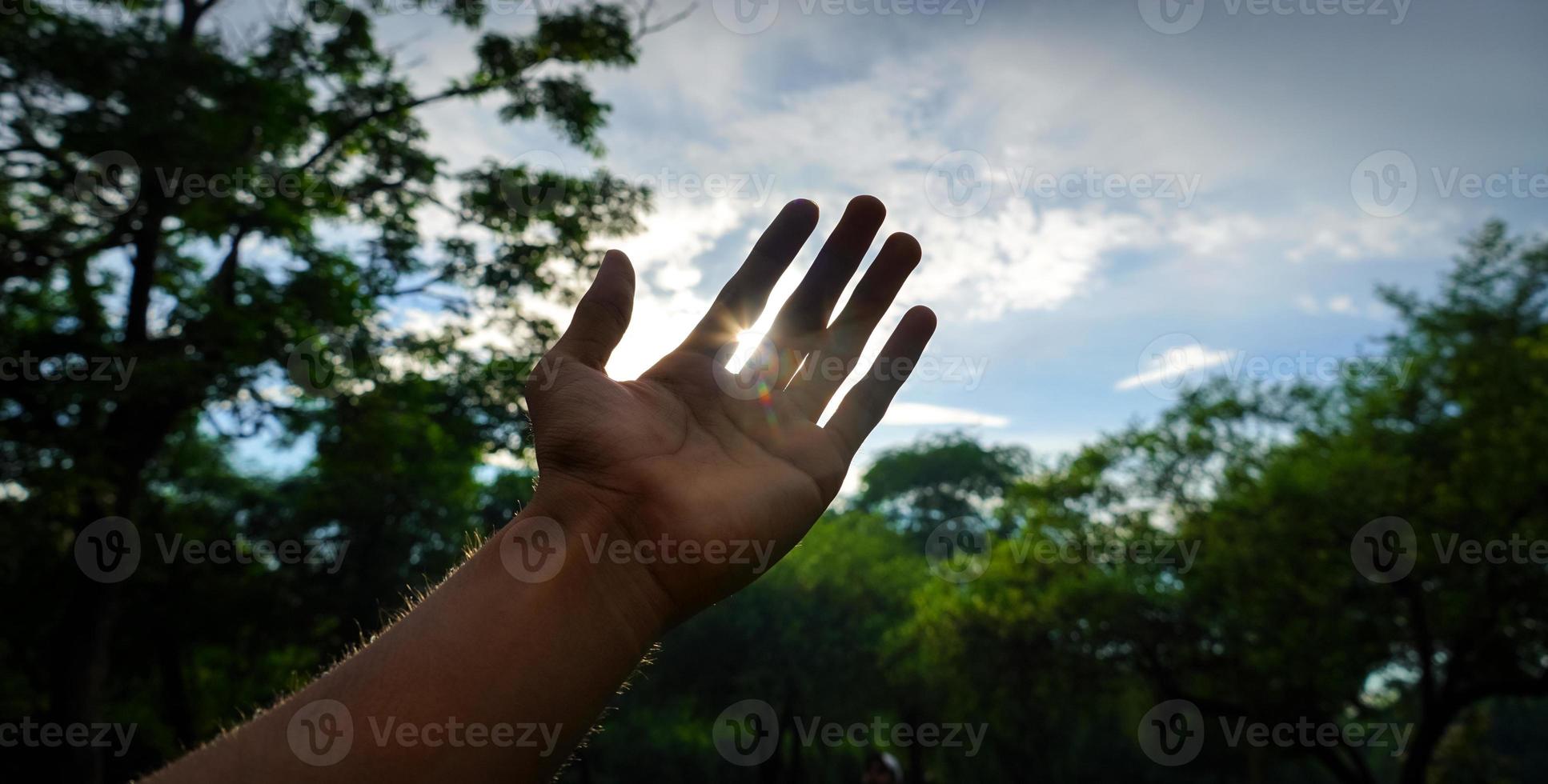 hand trying to touch the rays of sun photo