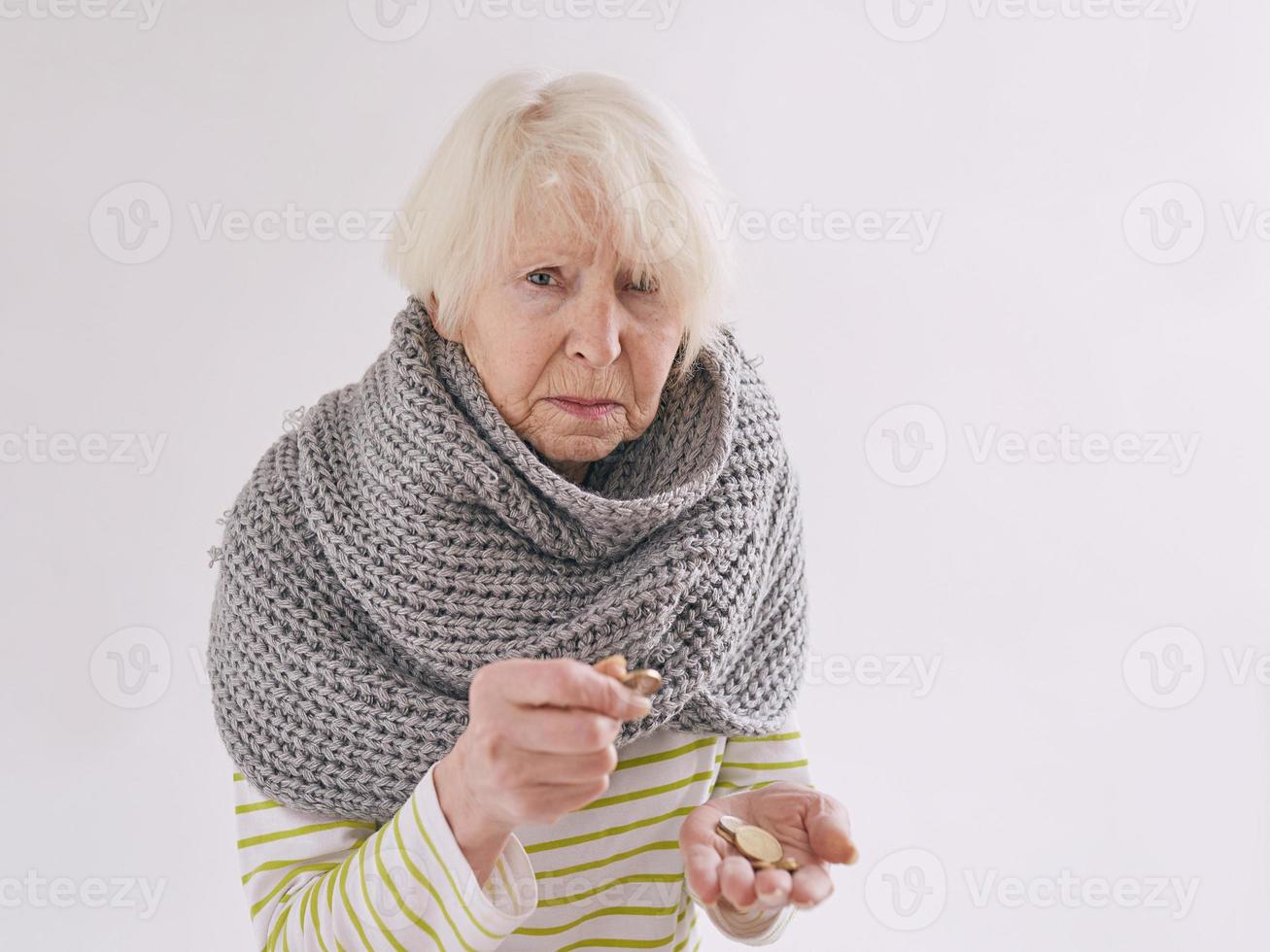 mujer mayor en bufanda contando monedas. pobreza, crisis, concepto de vejez foto