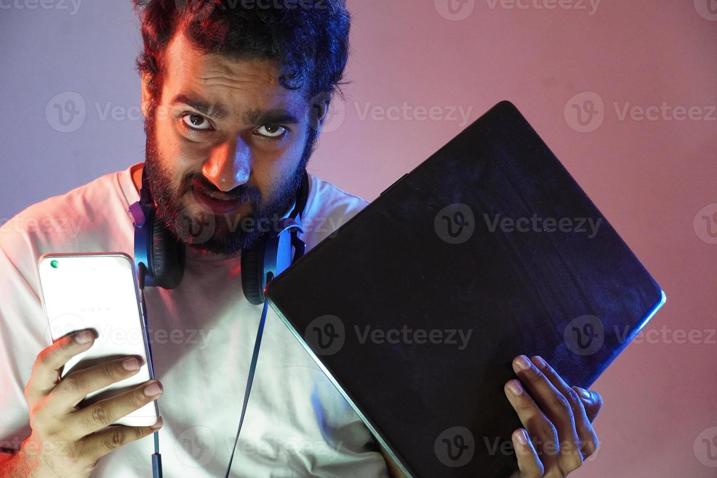 a hacker boy having laptop and mobile and anger face photo
