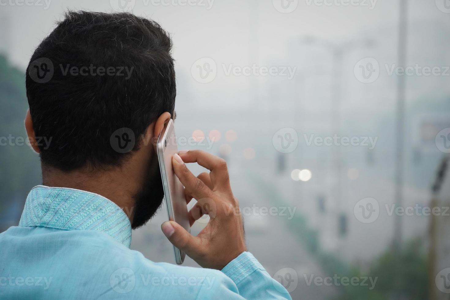 indian man standing on flyover bridge and talk on phone photo