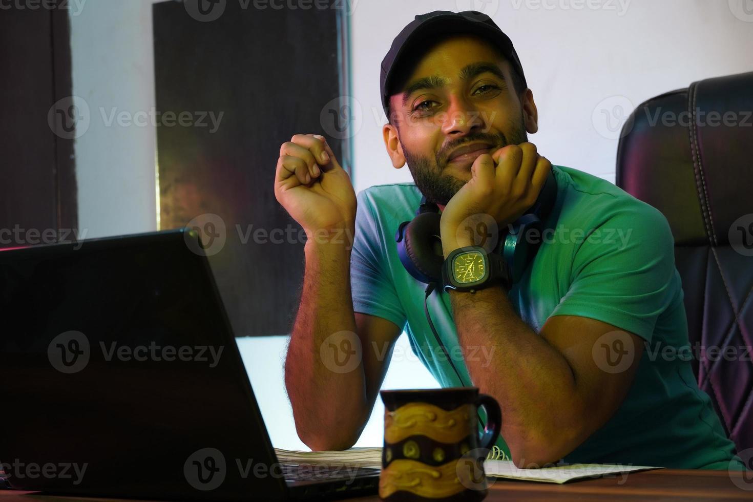 chico indio sonriente con computadora portátil trabajando o estudiando en línea foto
