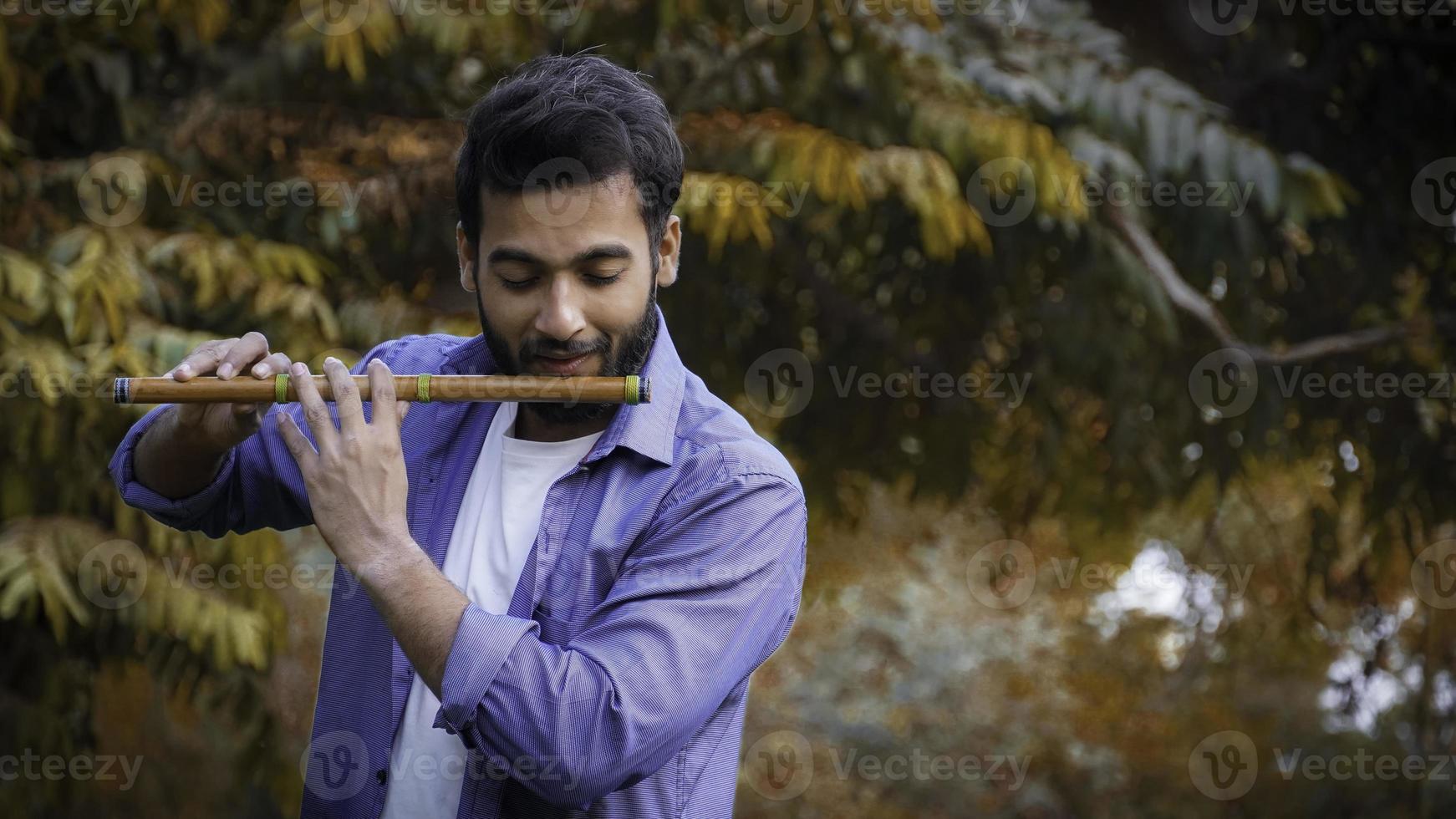 Flute player playing Flute During Autumn - Indian Handsome Flute Player Images photo
