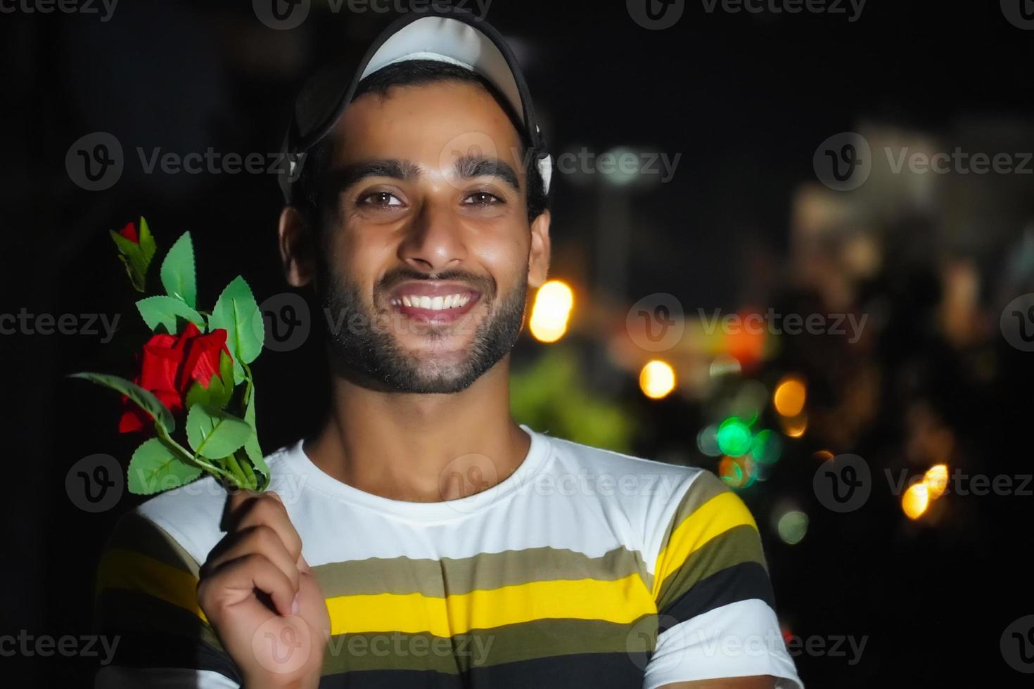 handsome man in holding red rose in hand , on roof photo