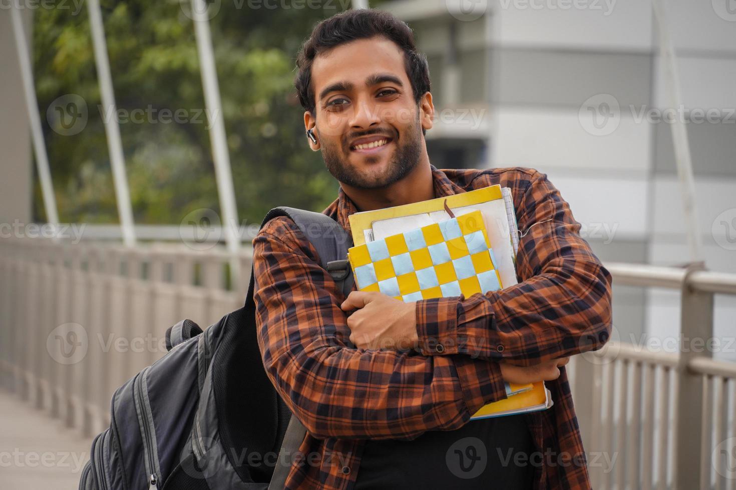 joven estudiante universitario con saco de arena de libro sonriendo frente a la cámara foto