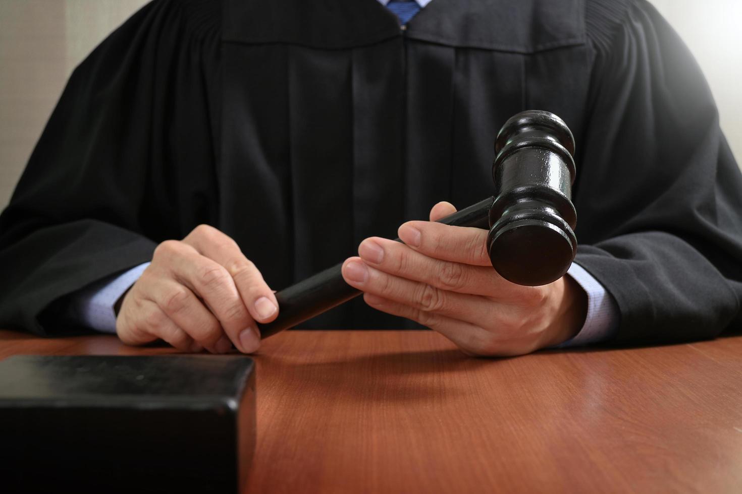 justice and law concept.Male judge in a courtroom striking the gavel,working with digital tablet computer docking keyboard on wood table photo