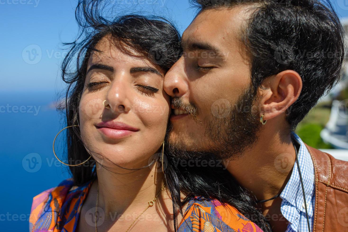 A man and a woman are hugging against the backdrop of Skaros Rock on Santorini Island. The village of Imerovigli. photo