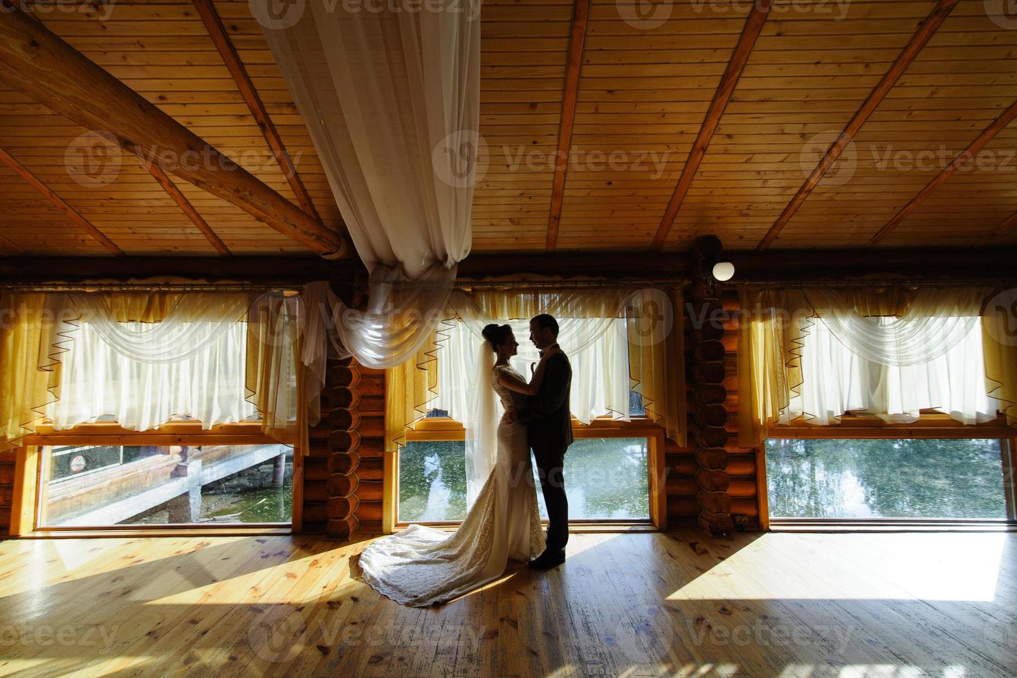 retrato de la novia y el novio en una habitación de hotel con grandes ventanales. foto