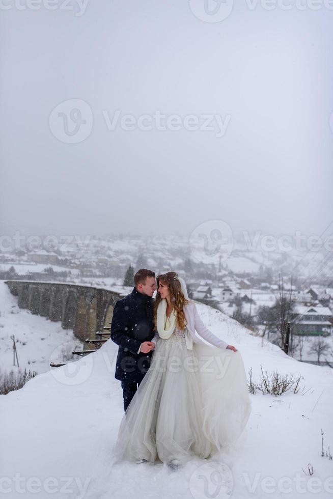 The groom leads his bride by the hand to a lonely old beech. Winter wedding. Place for a logo. photo