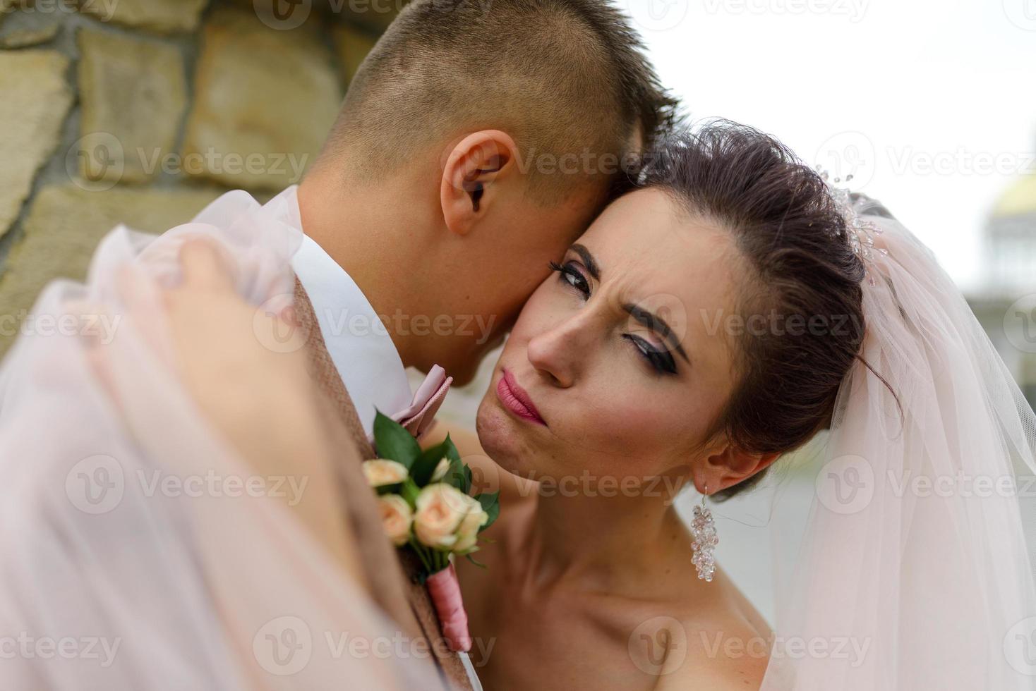 The bride and groom hug under a veil and gently bowed their heads to each other. photo