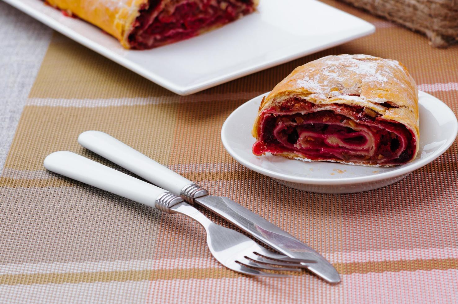 rollo casero con mermelada en un plato blanco con tenedor y cuchillo foto