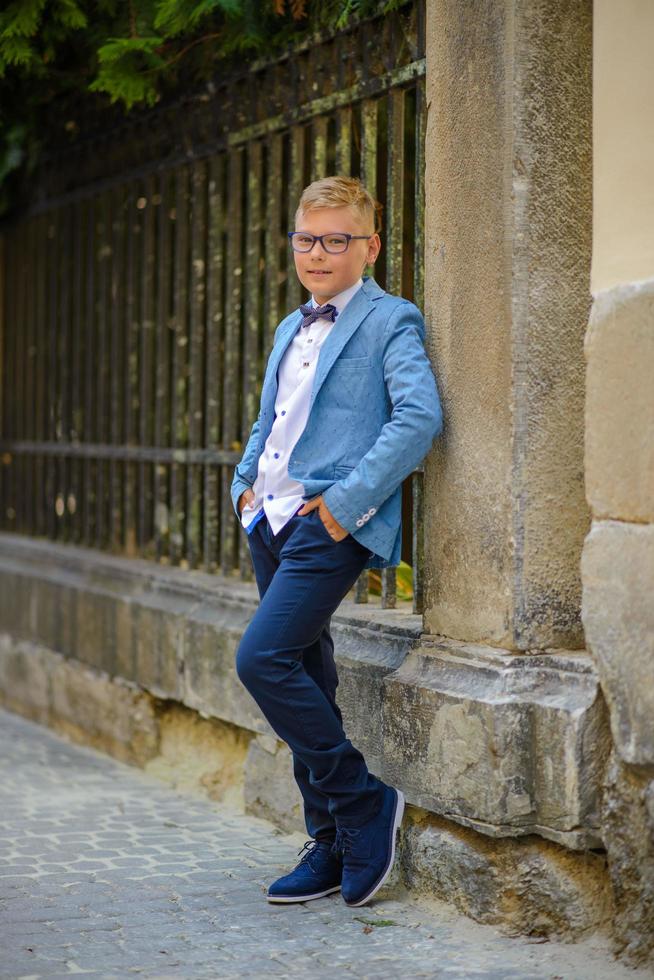 dos niños pequeños, los hermanos están vestidos con traje. los niños están parados en el parque y abrazándose. foto