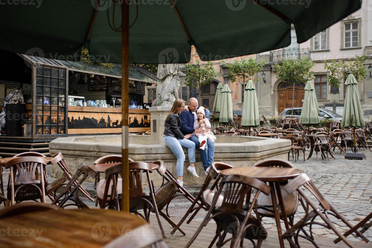 los padres y su hija están sentados en los escalones de una antigua iglesia. foto