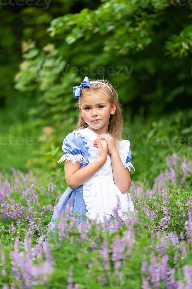 retrato de una niña linda vestida como alice. sesión de fotos estilizada en la naturaleza.