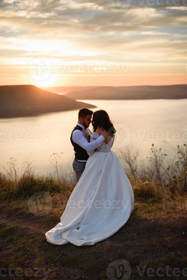 la novia y el novio caminan cerca del antiguo castillo. la pareja está de espaldas el uno al otro. foto