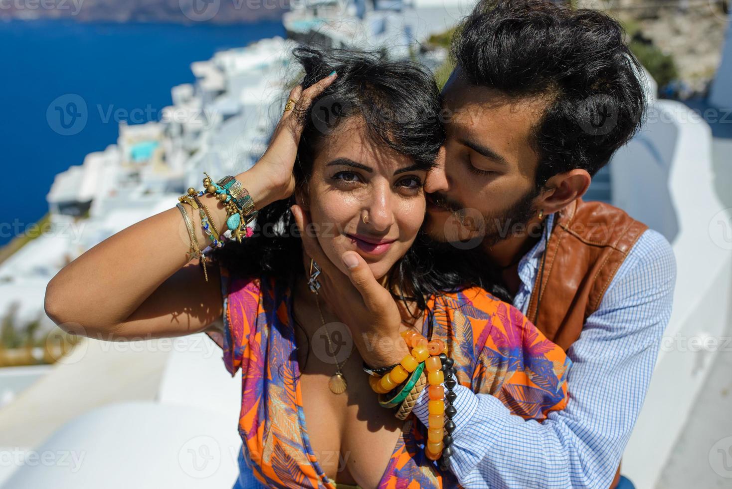 A man and a woman are hugging against the backdrop of Skaros Rock on Santorini Island. The village of Imerovigli. photo
