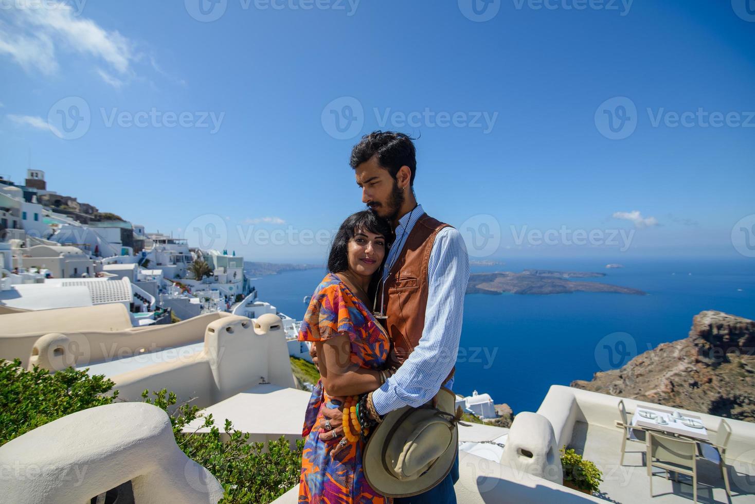 A man and a woman are hugging against the backdrop of Skaros Rock on Santorini Island. The village of Imerovigli. photo