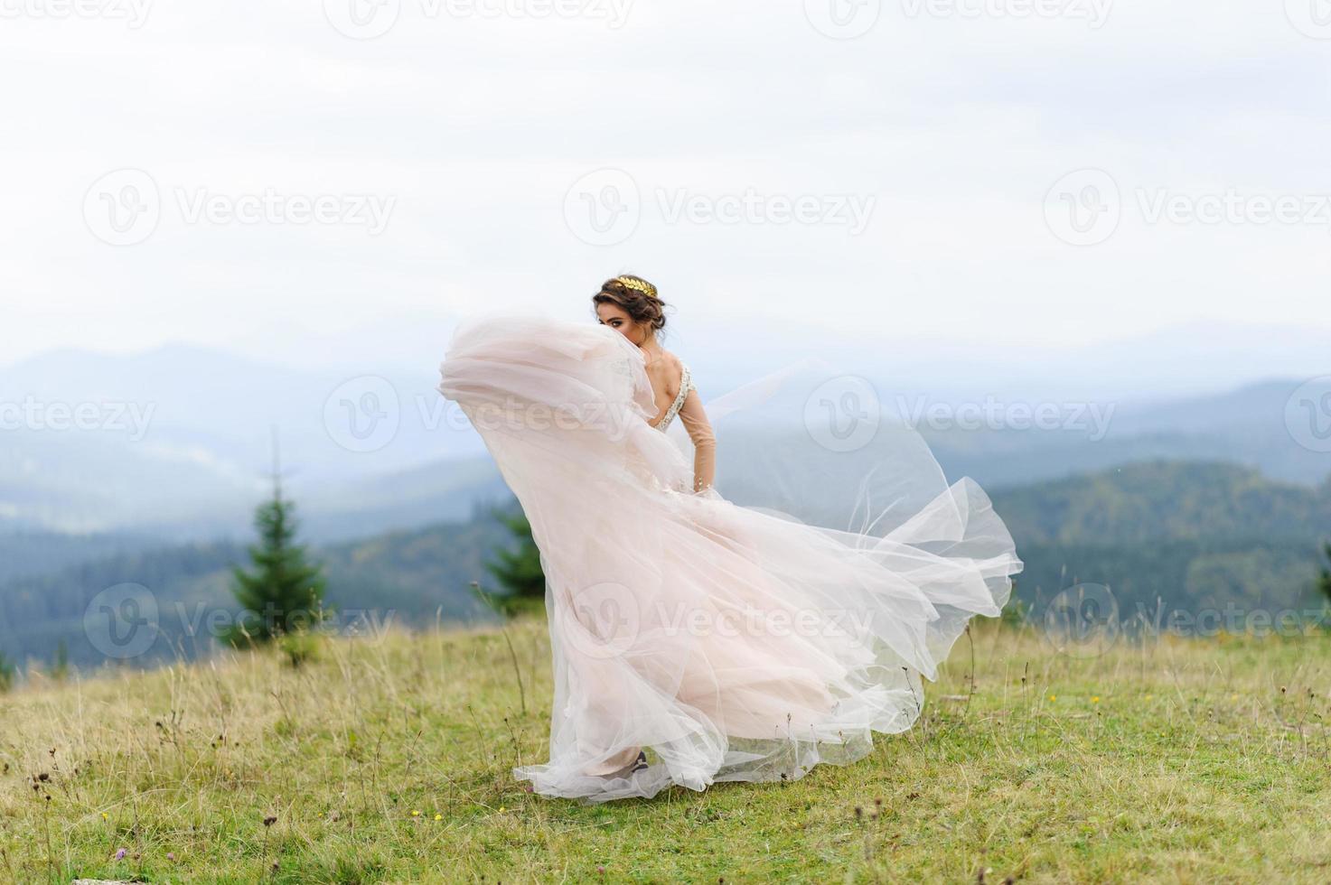 The bride in a pink airy dress swirls and plays with her dress. photo