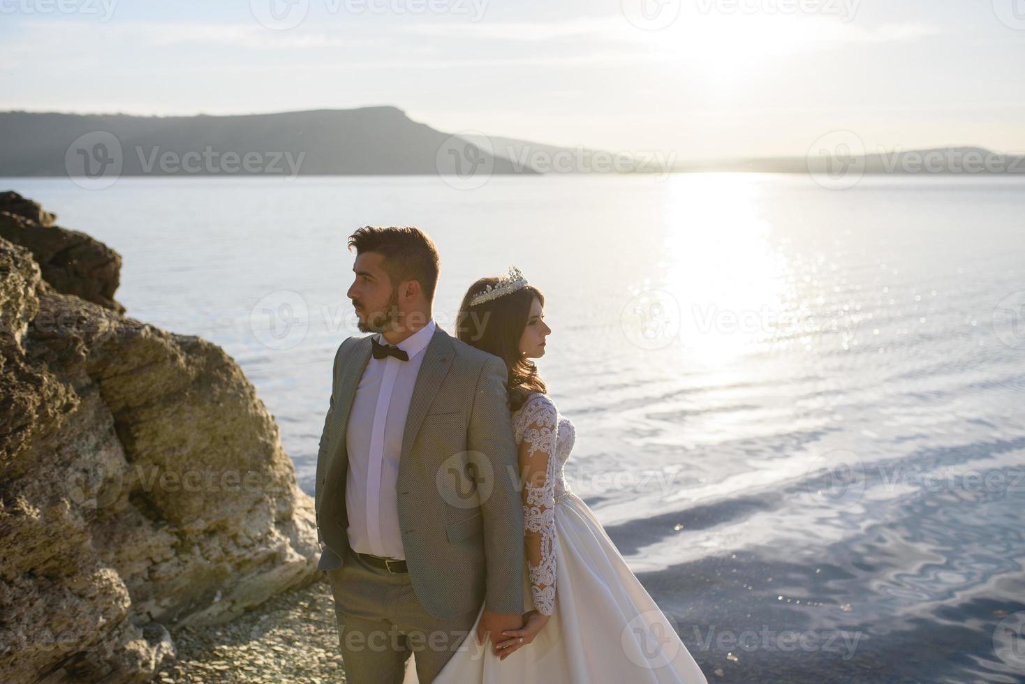 The bride and groom are walking near the old castle. The couple stands with their backs to each other. photo