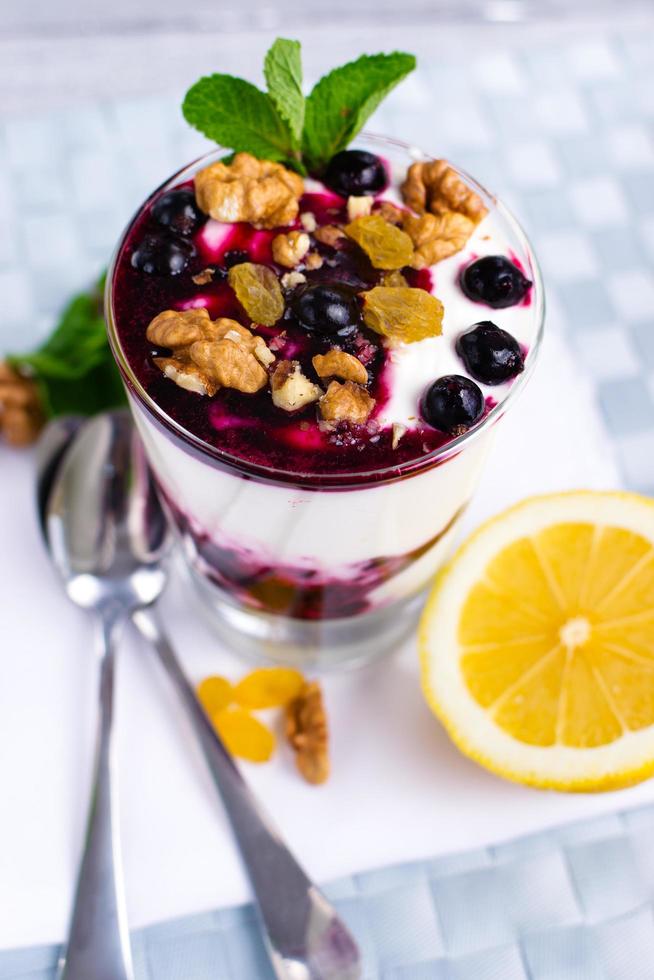 cream dessert with berries, black currant jam and nuts decorated with mint leaves photo