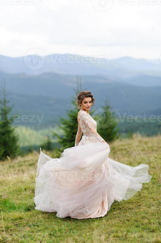 The bride in a pink airy dress swirls and plays with her dress. photo