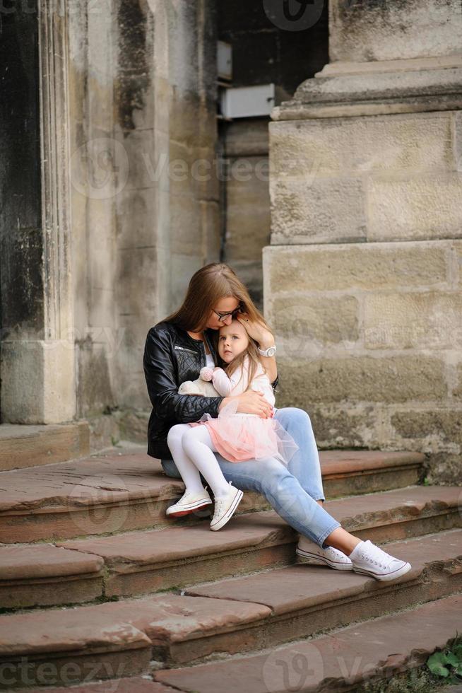 Parents and their daughter are sitting on the steps of an old church. photo