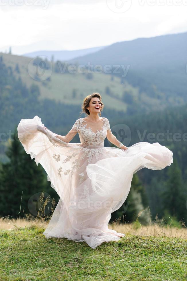 la novia con un vestido rosa aireado gira y juega con su vestido. foto