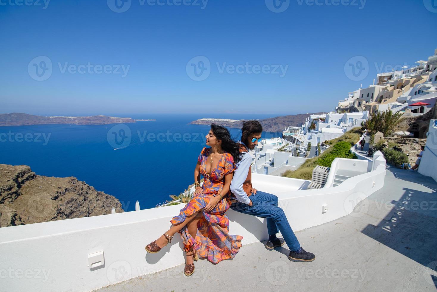 A man and a woman are hugging against the backdrop of Skaros Rock on Santorini Island. The village of Imerovigli. photo