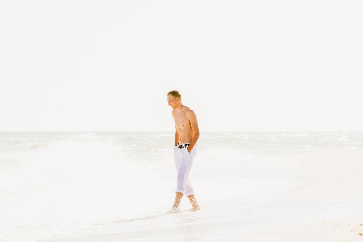 un hombre caminando por la orilla del mar foto