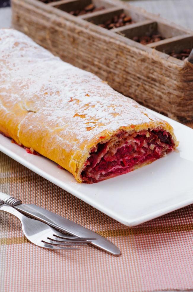 homemade roll with jam on a white plate with a fork and knife photo