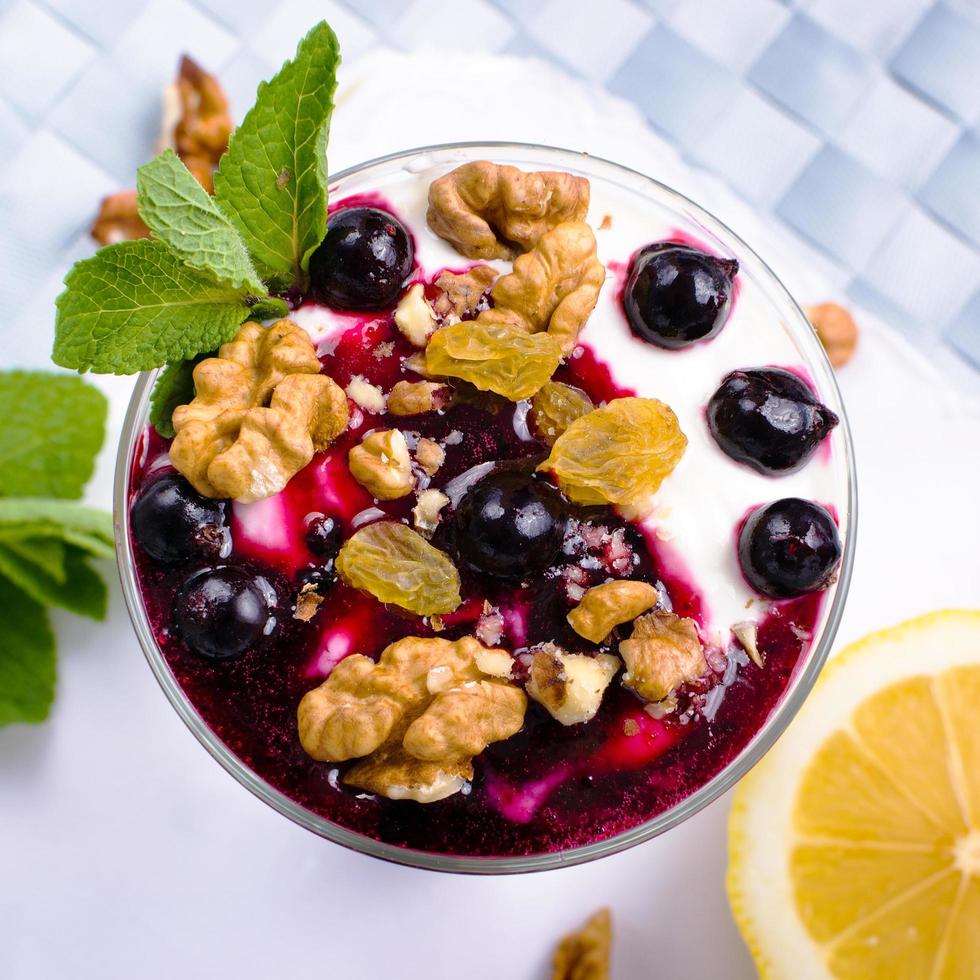 cream dessert with berries, black currant jam and nuts decorated with mint leaves photo