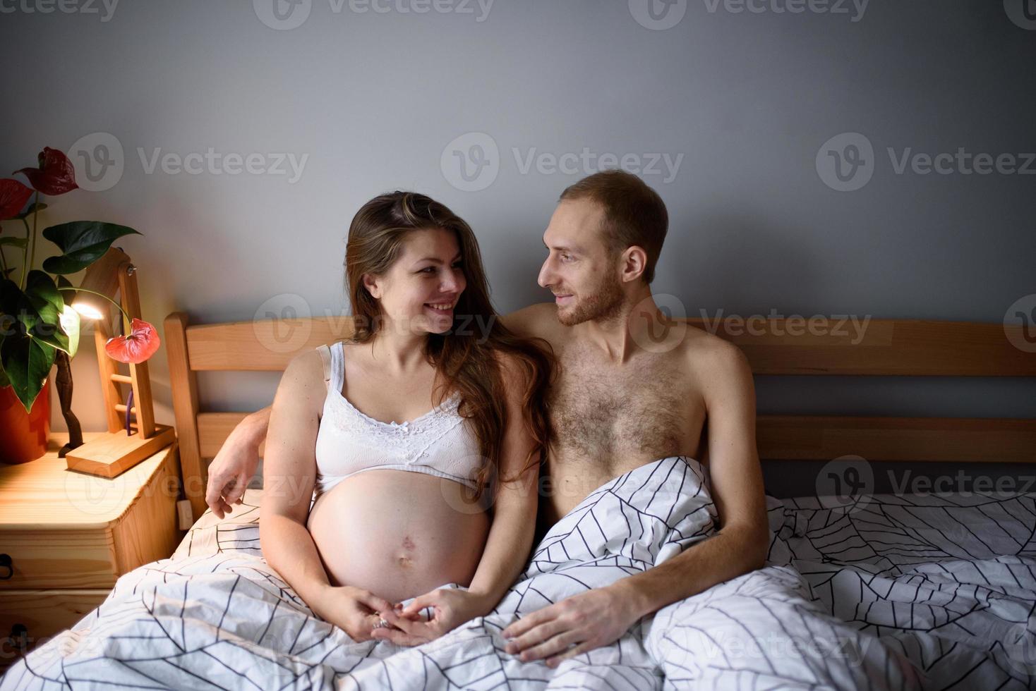 Pregnant couple during quarantine have fun in their bed. photo