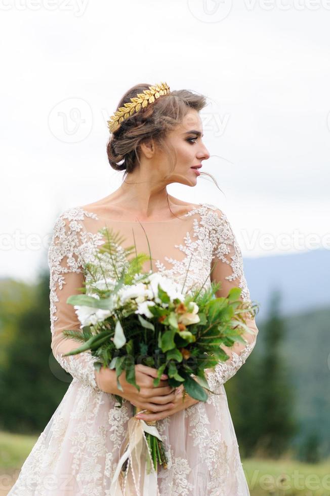Portrait of a beautiful bride in the mountains. The girl holds a wedding bouquet in her hands. photo