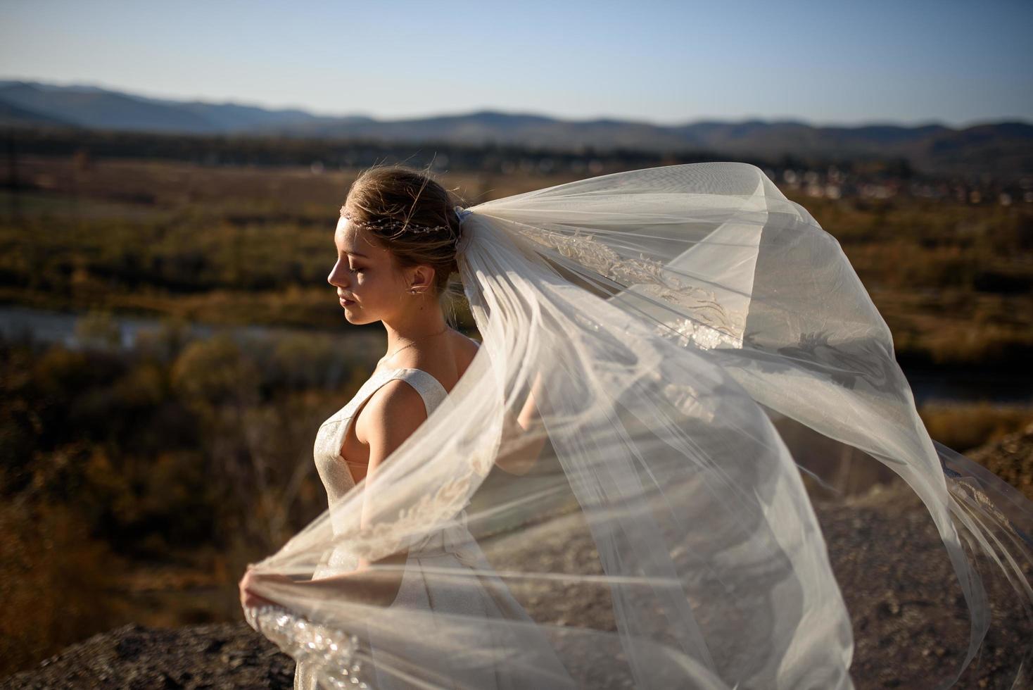 retrato de una joven novia hermosa en las montañas con un velo. el viento desarrolla un velo. fotografía de boda en la montaña. foto