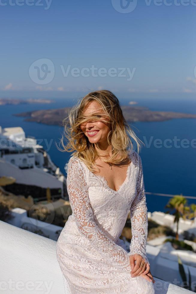 bella novia con un vestido blanco posando en el contexto de la ciudad de thira, santorini. foto