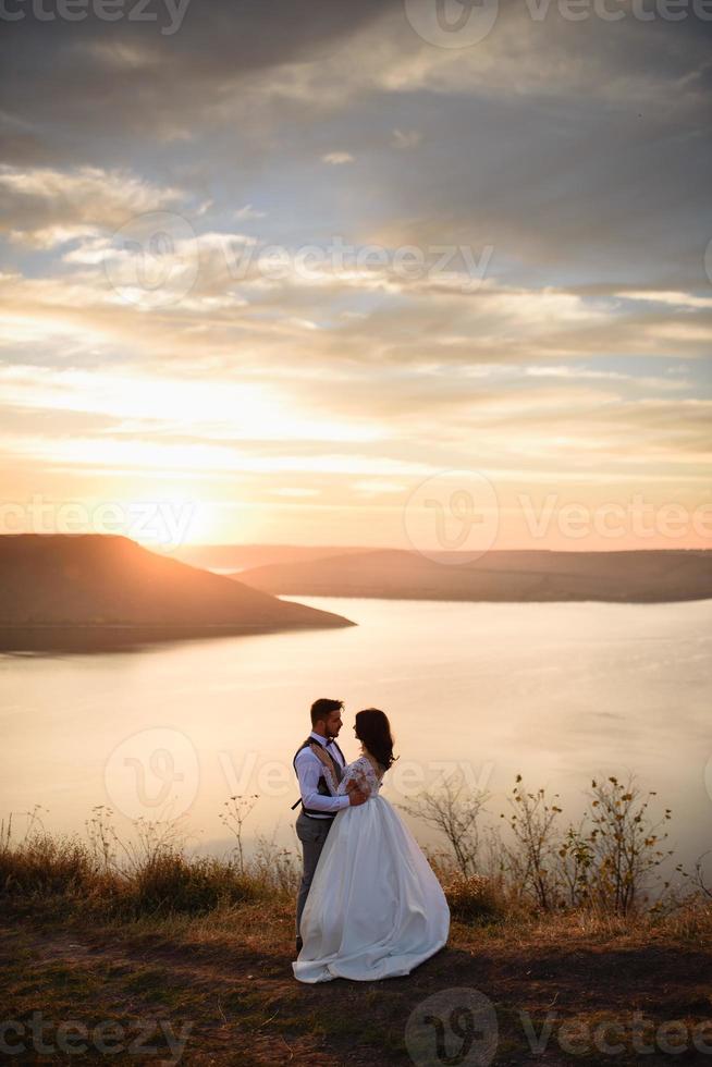 la novia y el novio caminan cerca del antiguo castillo. la pareja está de espaldas el uno al otro. foto