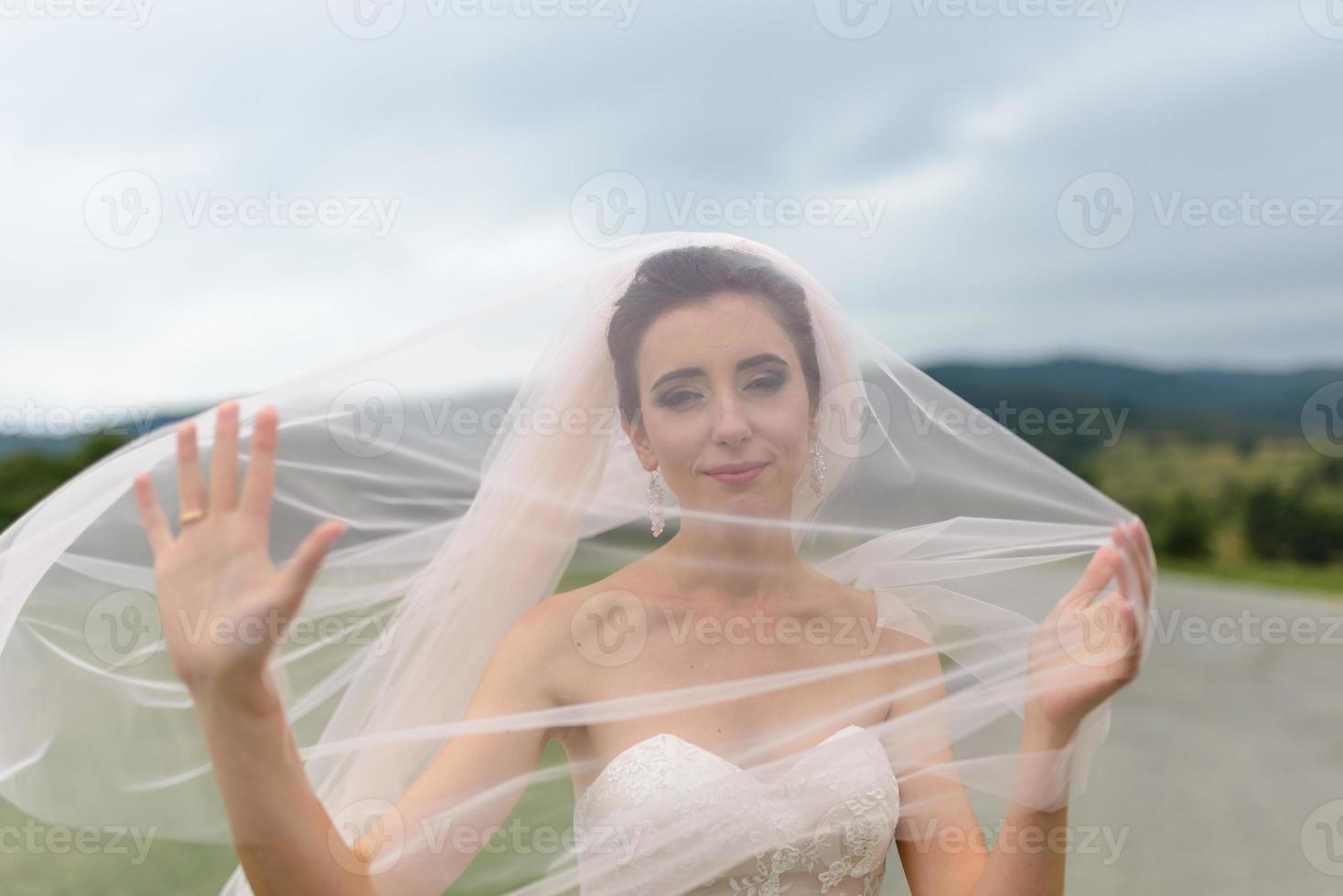 The bride and groom hug under a veil and gently bowed their heads to each other. photo