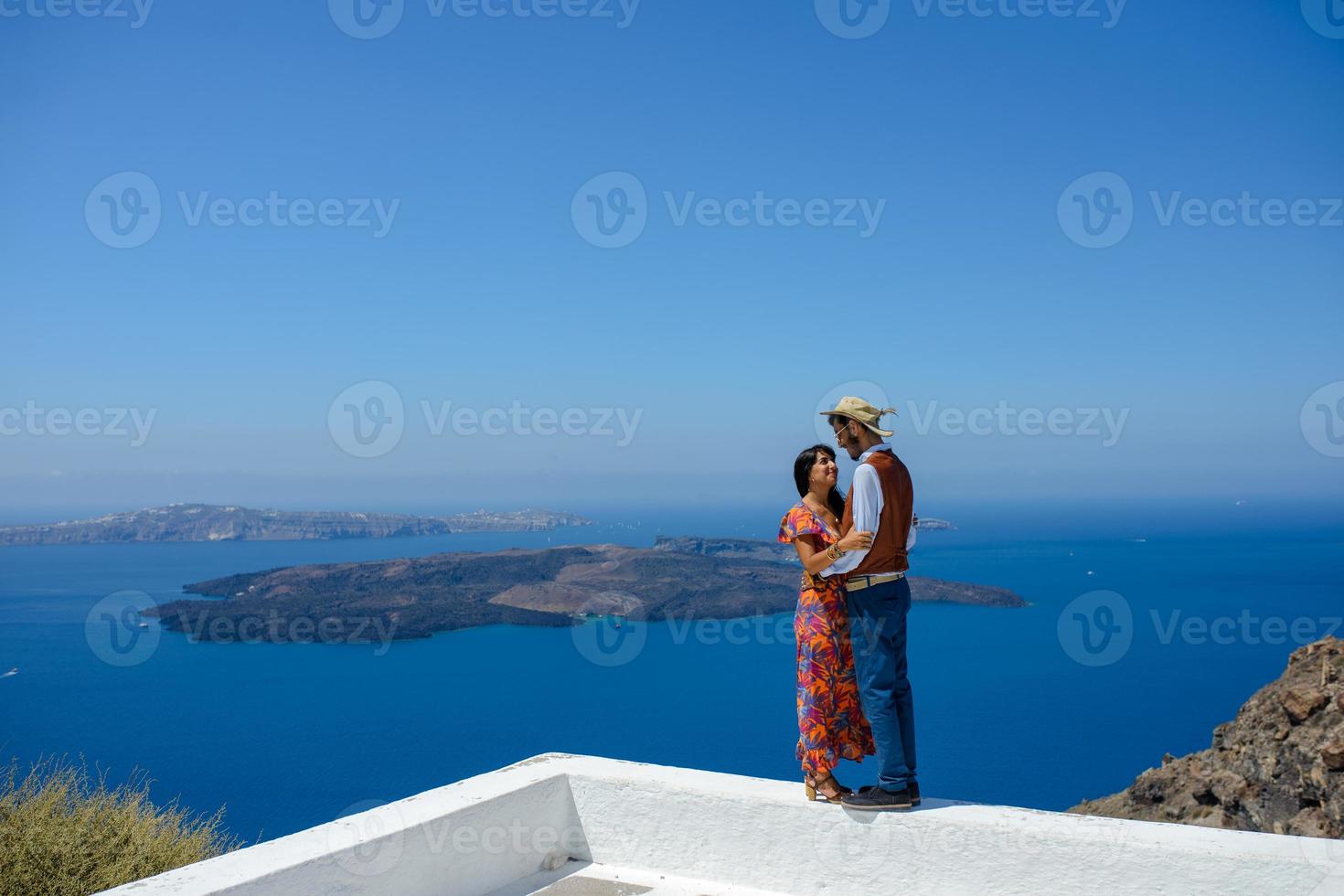 A man and a woman are hugging against the backdrop of Skaros Rock on Santorini Island. The village of Imerovigli. photo
