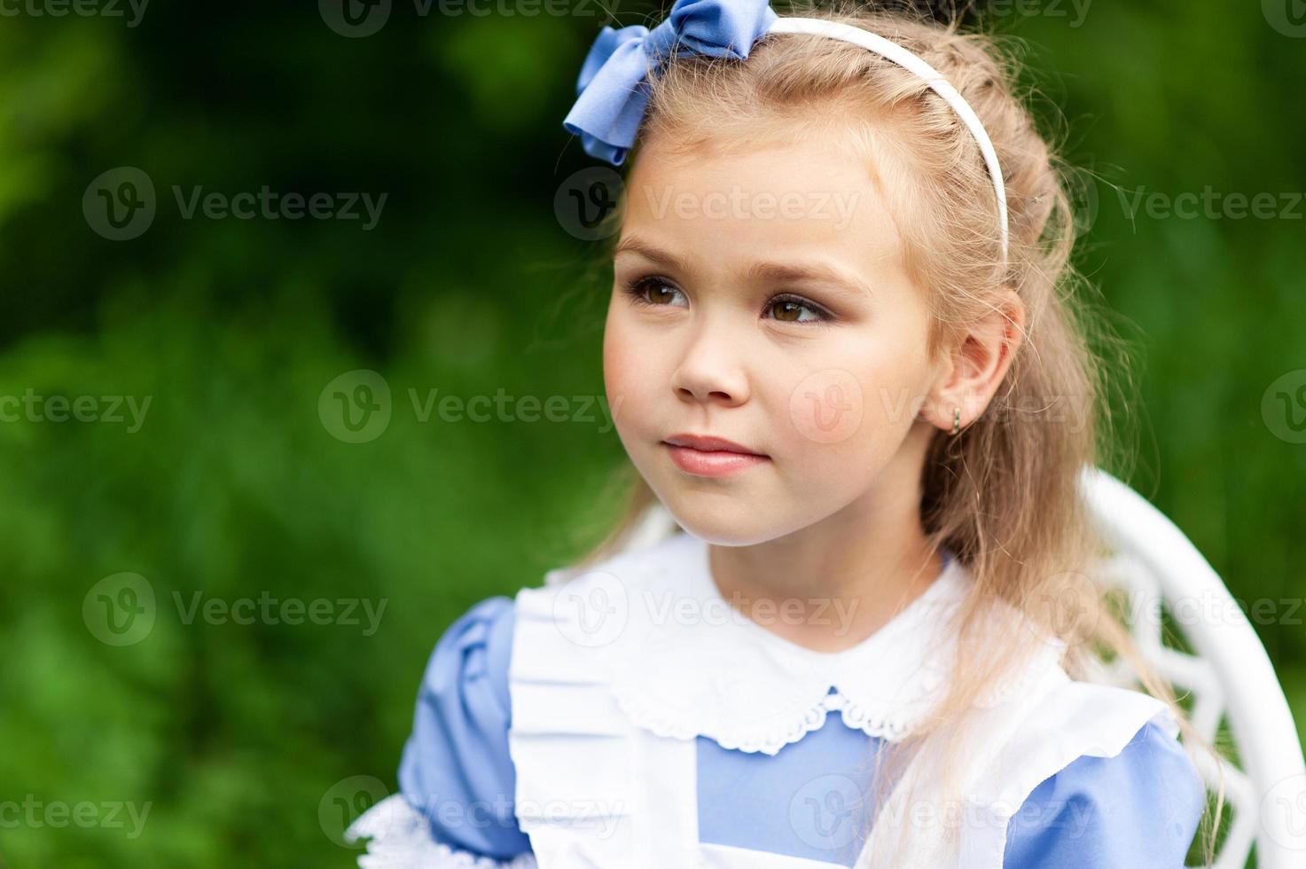 Portrait of a little cute girl dressed as Alice. Stylized photo shoot in nature.