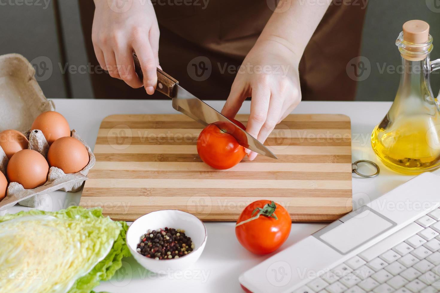 mujer bloguera graba receta de ensalada dietética en cámara. lecciones de cocina en línea, usando una computadora portátil en la cocina. foto